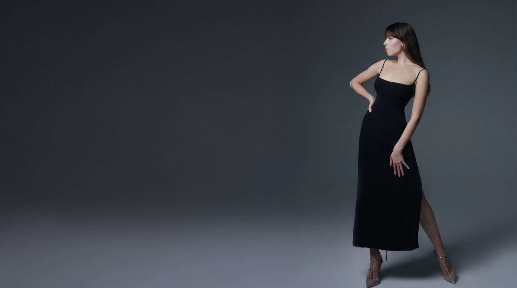 Yulia Pavlishcheva de pie con un vestido negro sobre fondo gris.